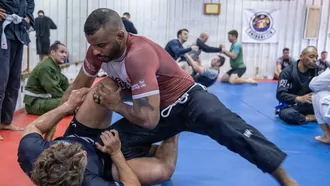 Muscular grappler in a rash guard passing guard during a no-gi BJJ class